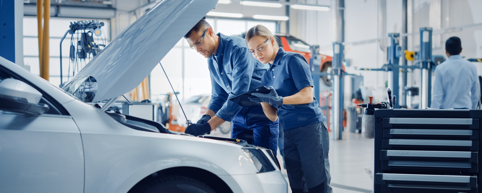 male and female technician in a workshop working on a car