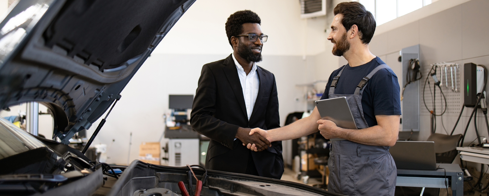 Two men shaking hands in a repair garage