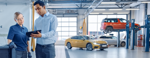 Two people in a garage looking at maintenance schedules